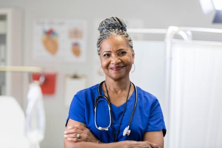 Woman wearing blue nurse attire smile for a picture