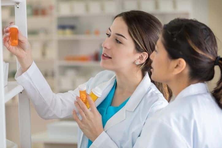 Two pharmacists looking at the bottle of medicine